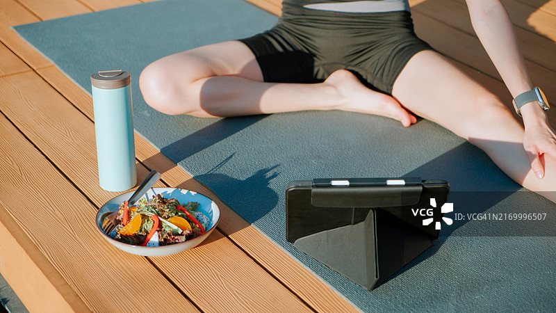 在房屋前院做瑜伽的亚洲年轻女子图片素材