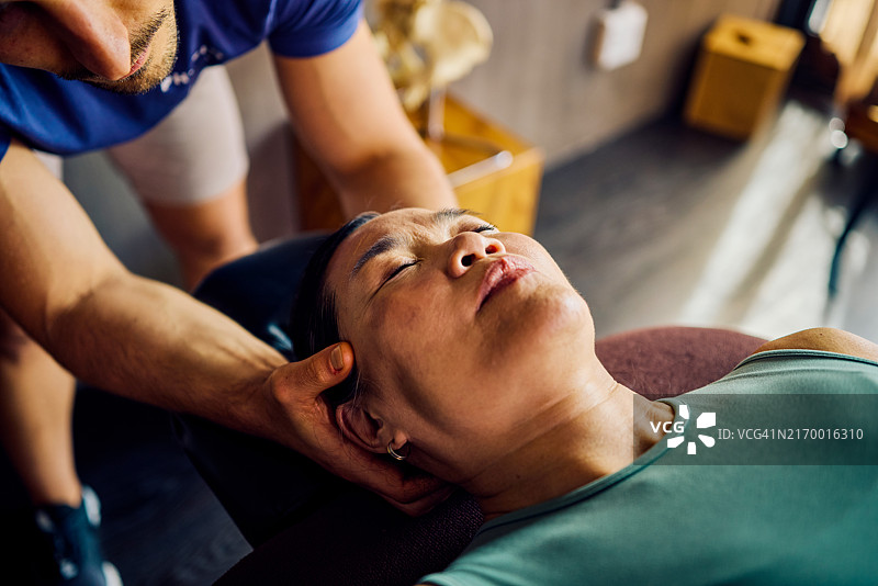 理疗师协助女患者进行颈部伸展运动，康复诊所特写镜头，医疗保健和物理治疗概念图片素材