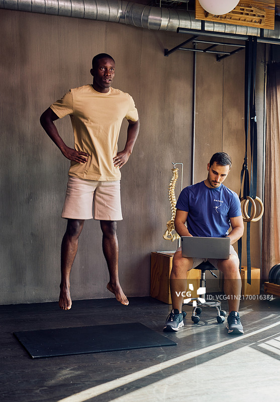 理疗师指导男患者进行跳跃训练，康复诊所全身照，医疗保健和物理治疗概念图片素材