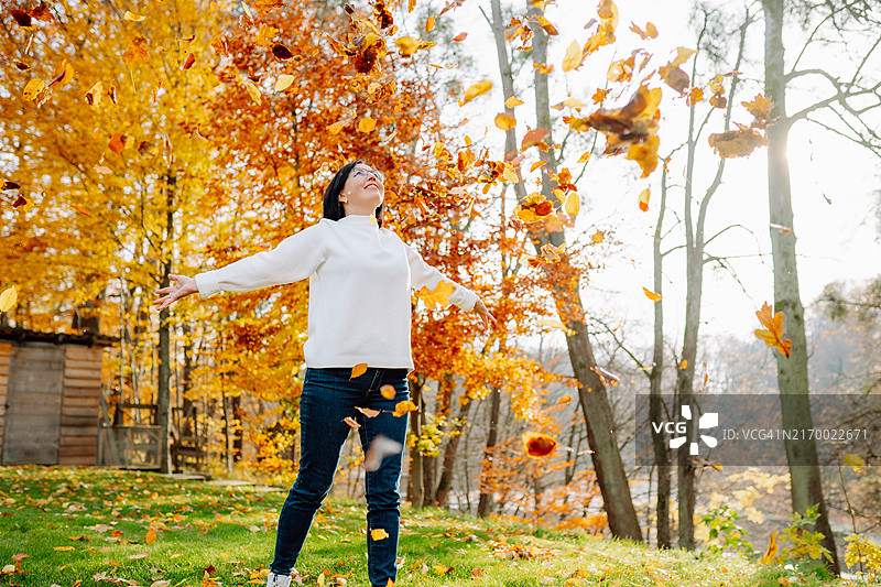 秋雨飞扬。异想天开的成熟的穿过落叶的帷幕，享受着秋叶的嬉戏。图片素材