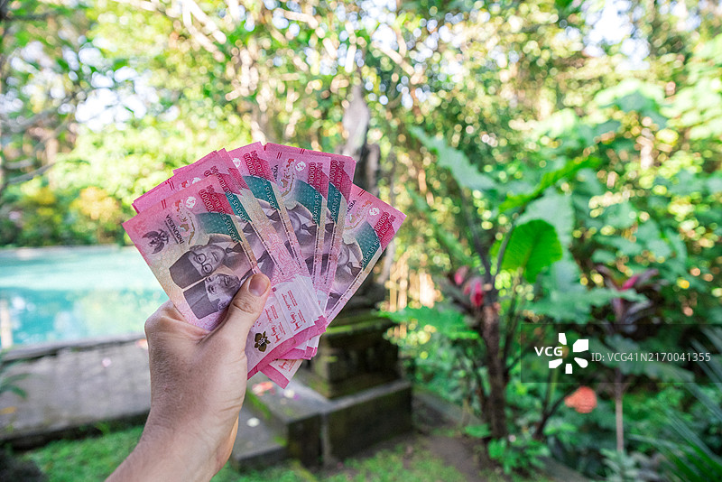 手持若干张印尼卢比纸币图片素材