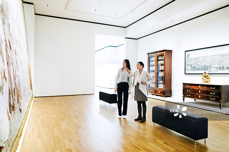 女士们探索美术馆内部，讨论壁画的细节图片素材