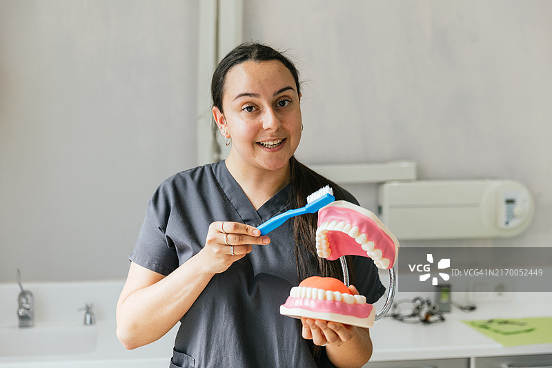女牙医拿着牙刷和假牙讲解口腔卫生图片素材