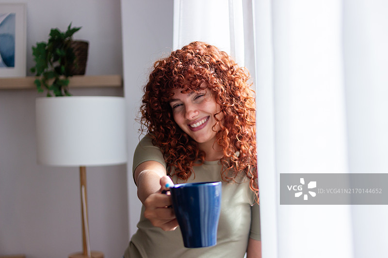 快乐的年轻女人在家提供一杯咖啡图片素材