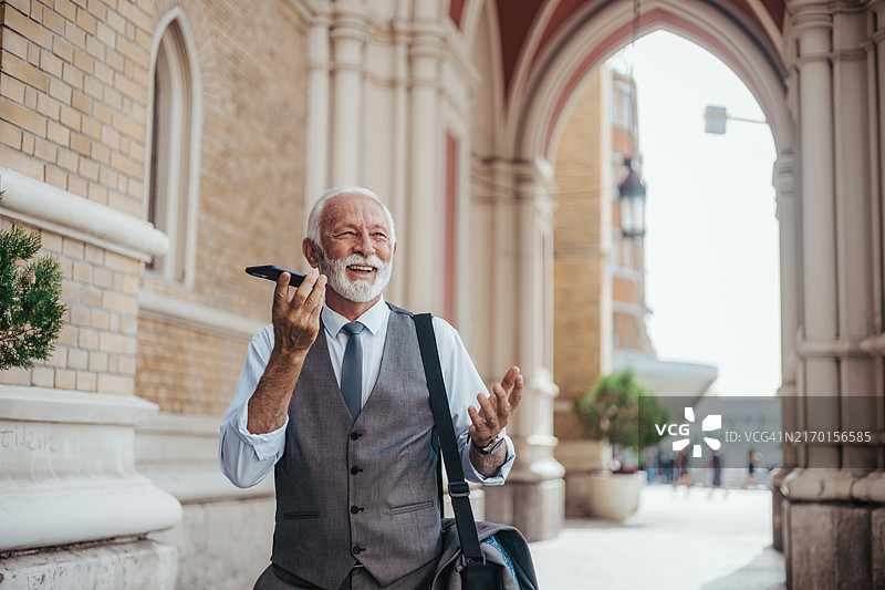 老年男人在历史建筑外进行视频通话图片素材