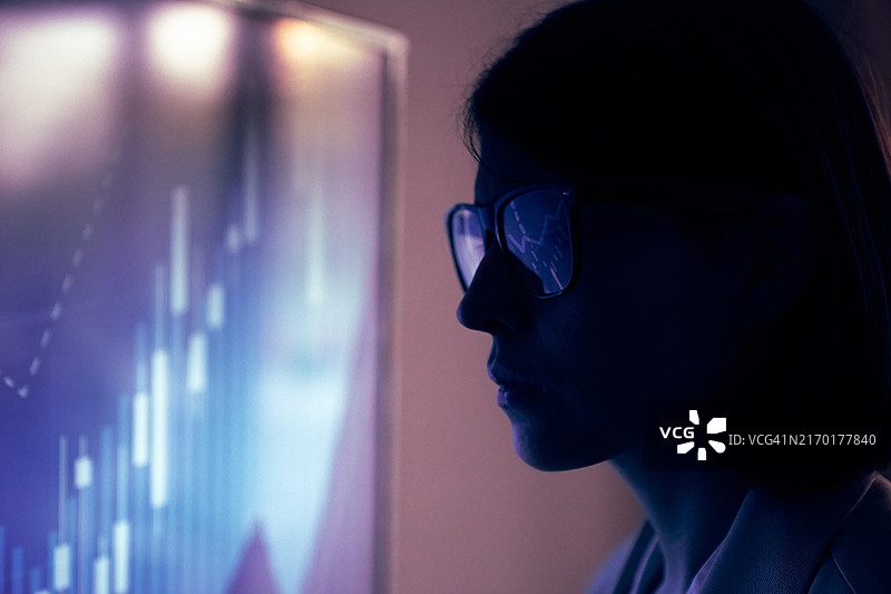 戴眼镜的商务女性在投资图表背景下的特写图片素材