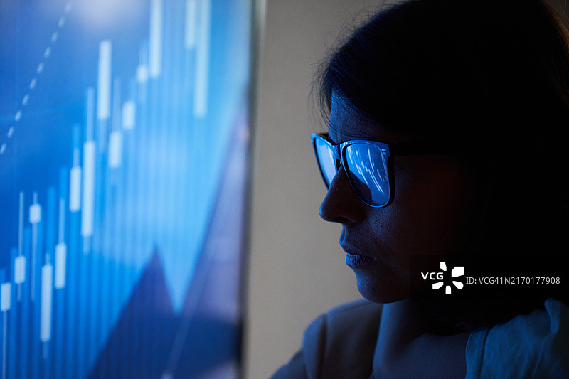 戴眼镜的商务女性在投资图表背景下的特写图片素材