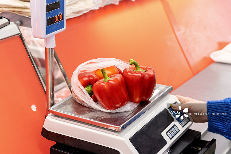 在电子市场秤上称量新鲜的红色甜椒图片素材