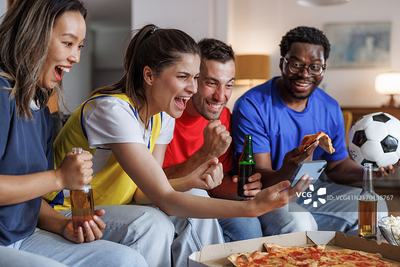 朋友们在智能手机上观看足球比赛时欢呼图片素材
