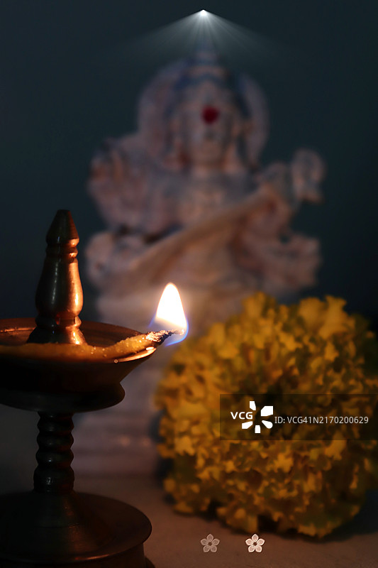 萨拉斯瓦蒂女神白色神像、点亮的黄铜油灯和万寿菊花/九夜节图片素材