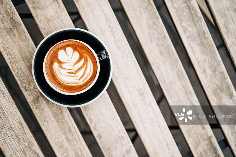 木桌上精美的拿铁艺术咖啡图片素材