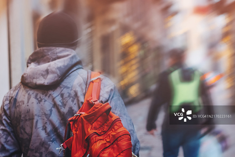 背着红色背包走在城市街道上的游客后视图图片素材