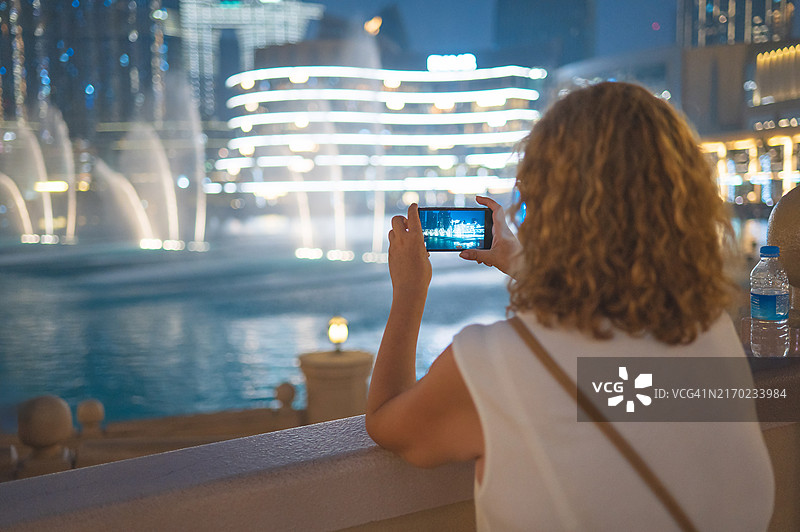 女人拍摄迪拜夜间喷泉表演图片素材
