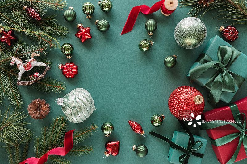 俯视：绿色背景上的圣诞礼物、冷杉树枝、圣诞球、装饰品、松果和丝带图片素材