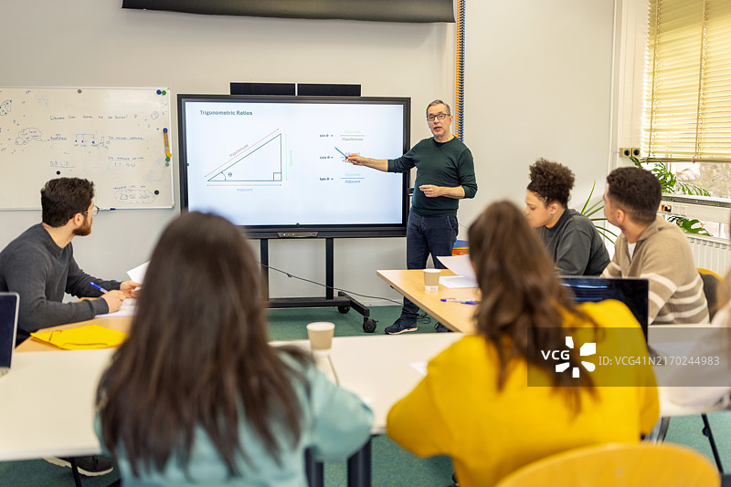 在成人教育课堂上使用大电视教学的年长教师图片素材