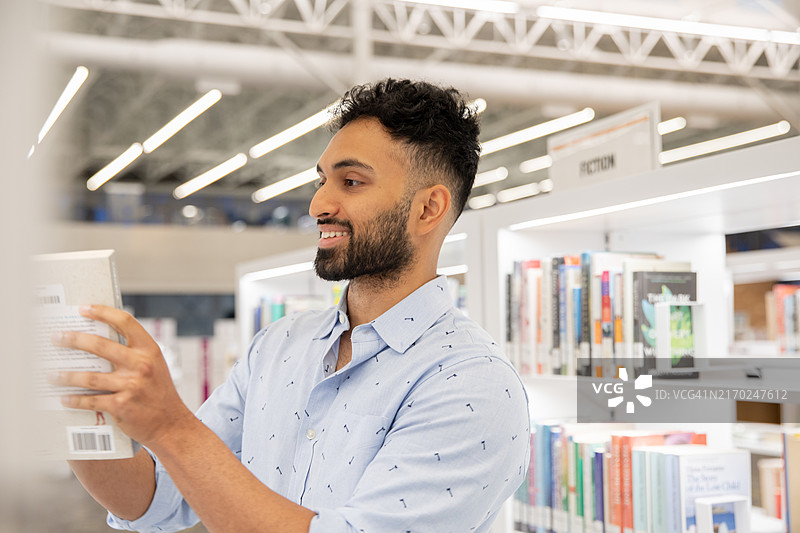 在图书馆书架上选书的年轻男人图片素材