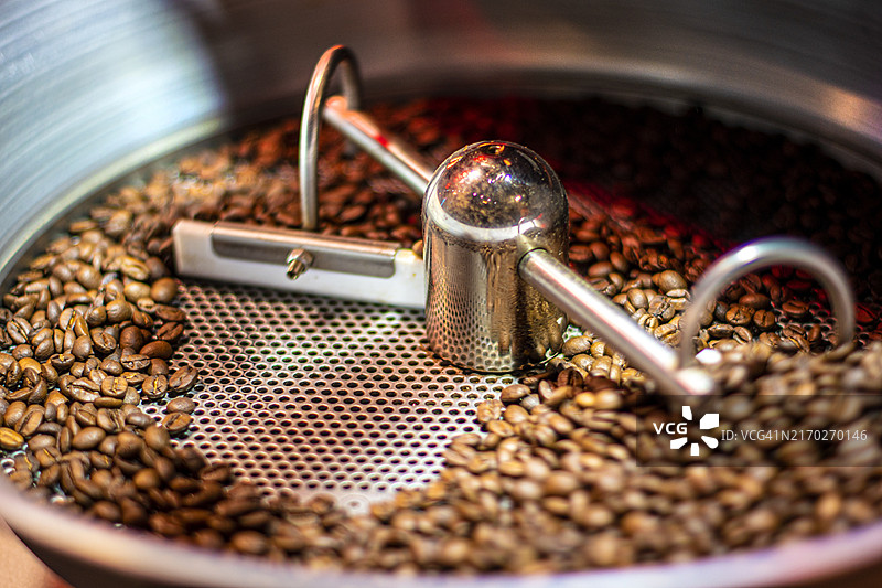 正在烘焙的咖啡豆。咖啡烘焙机。图片素材