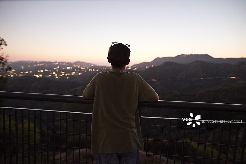 青少年男孩在黄昏时看着山丘图片素材