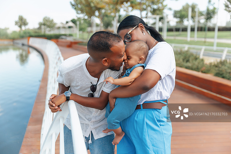 充满爱意的父母在湖边亲吻宝宝图片素材