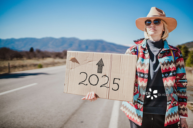 2025年：独自搭便车的女子举着纸板标志图片素材