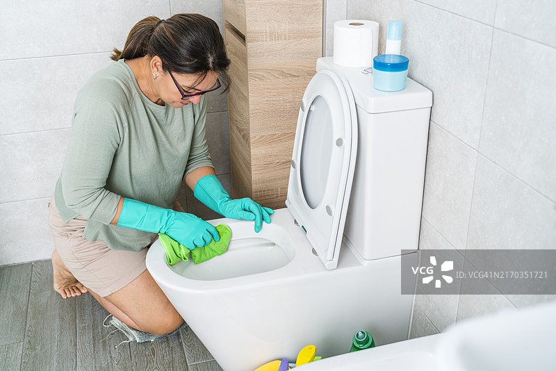 女人跪在浴室里用抹布擦拭马桶图片素材