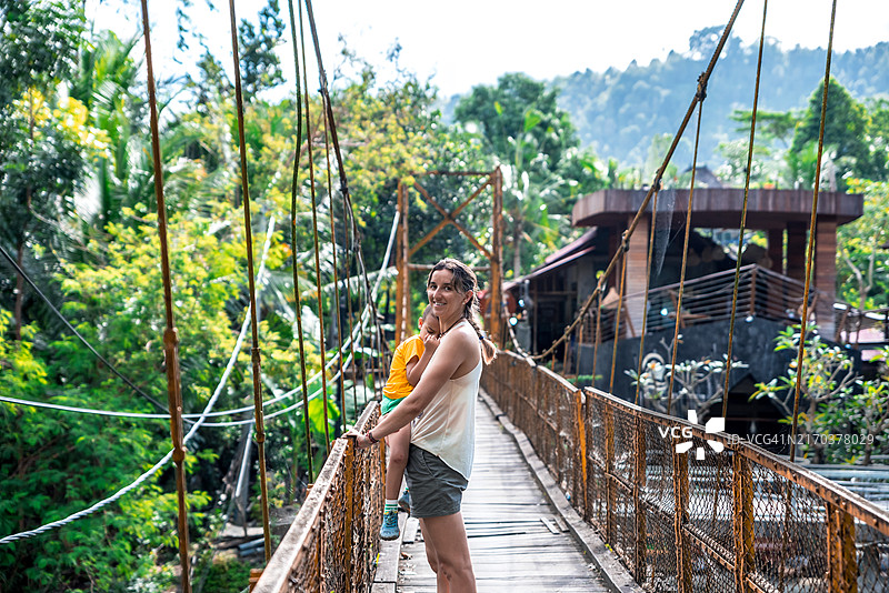 母亲抱着孩子漫步在锡德曼的黄桥上图片素材