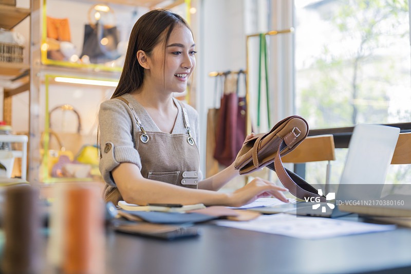皮革店：箱包设计师用笔记本电脑检查订单图片素材