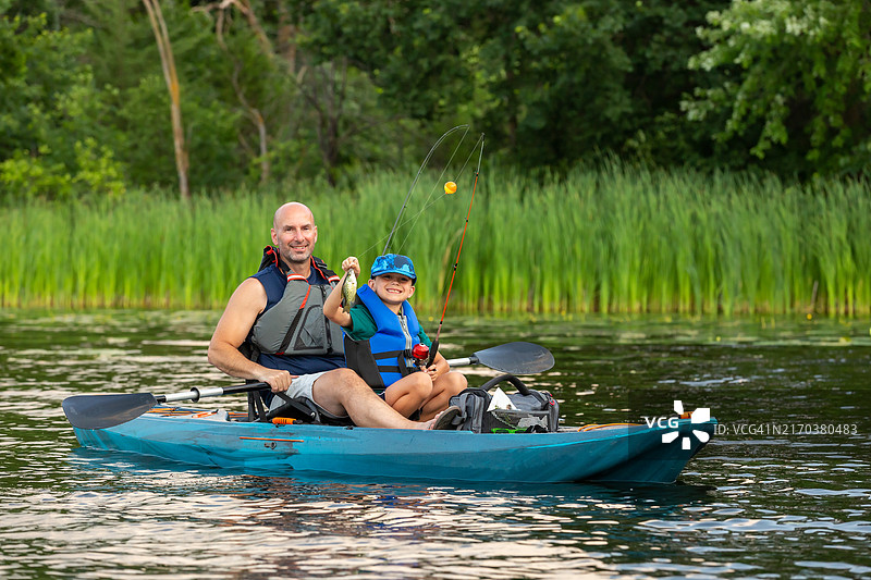 男孩手持皮划艇钓到的鱼图片素材