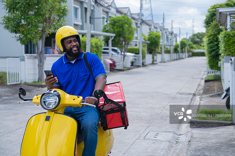 骑摩托车的快递员送餐，到达客户位置时致电客户。图片素材