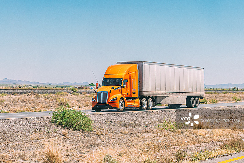 鲜艳的橙色半挂卡车在墨西哥奇瓦瓦州华雷斯城附近行驶图片素材