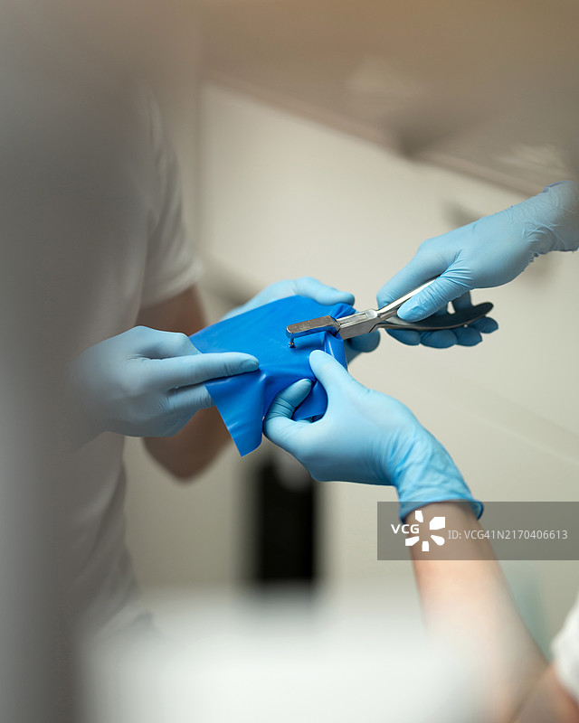 牙医准备橡皮障，牙科助手在橡皮障上为牙齿打孔，助手准备牙科器械，牙科助手手持橡皮障图片素材