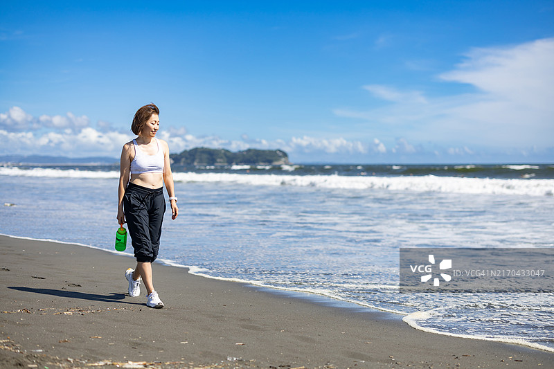 女人在社区的海滩上散步图片素材