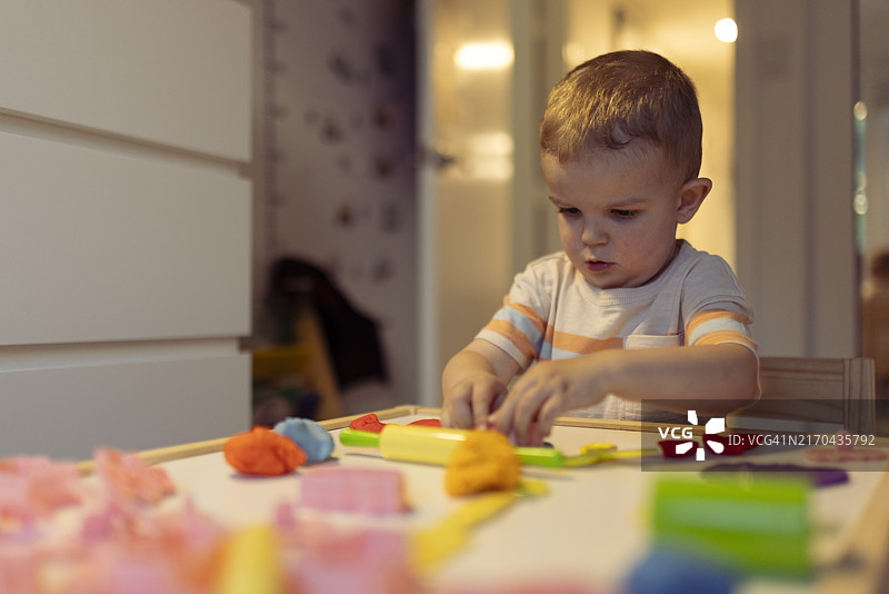 可爱男孩玩橡皮泥或彩泥图片素材