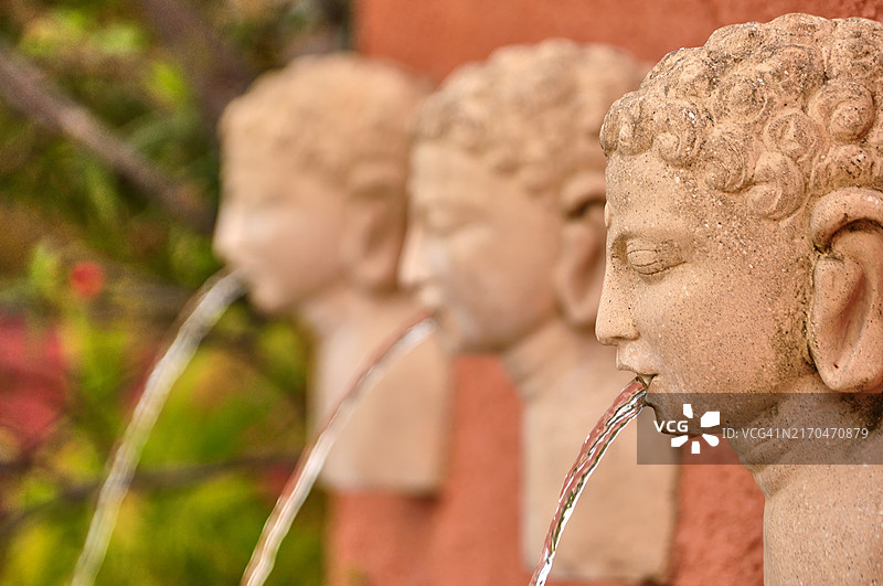 石佛头像喷泉，水从口中流出图片素材