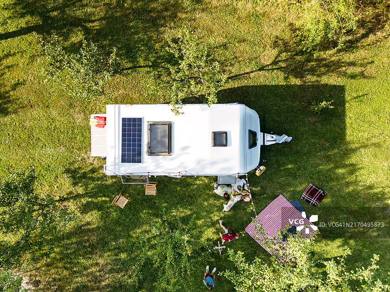 停放的房车俯视图，配有烧烤架和野餐毯。露营和探索新地方。房车前的野餐晚餐。图片素材