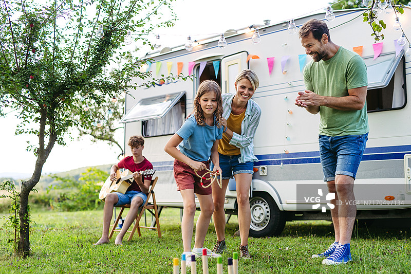 父母和女儿在户外玩游戏，玩得很开心。全家在房车里旅行，露营和探索新地方图片素材