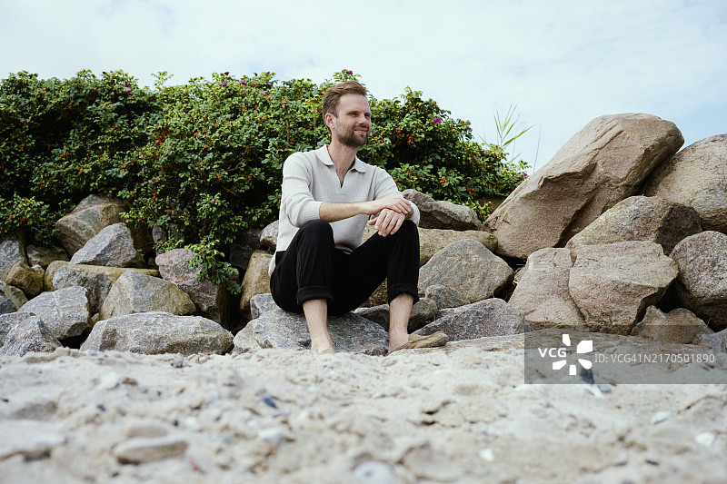 坐在海滩岩石上的男人图片素材