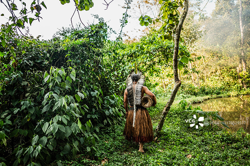 土著人带着捕鱼器在河边行走图片素材