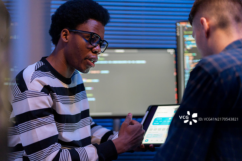 两位男开发人员在办公室工作，专注于改进电脑上的代码。他们正在开发一个以服务为基础的软件平台，旨在为具有创新技术解决方案的初创企业提供支持。图片素材