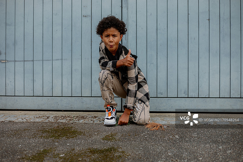 非裔美国男孩蹲在墙边看着镜头图片素材
