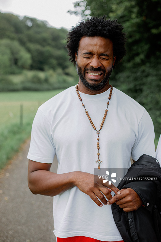 非裔美国男人在户外散步，闭着眼睛，笑着皱着眉头图片素材