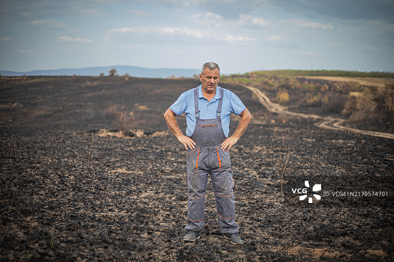 事故与灾难：男子望着烧毁的农田图片素材