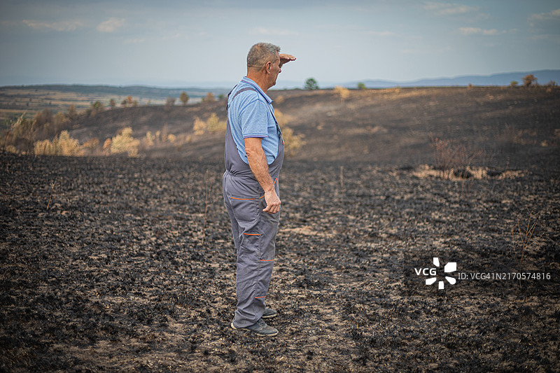 事故与灾难：男子望着烧毁的农田图片素材