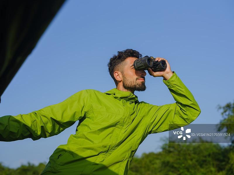 在旅行期间，用双筒望远镜从越野车里向外看的男人图片素材