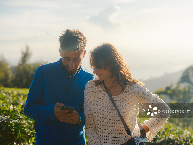 男人在斯里兰卡茶园向女人展示他的智能手机图片素材