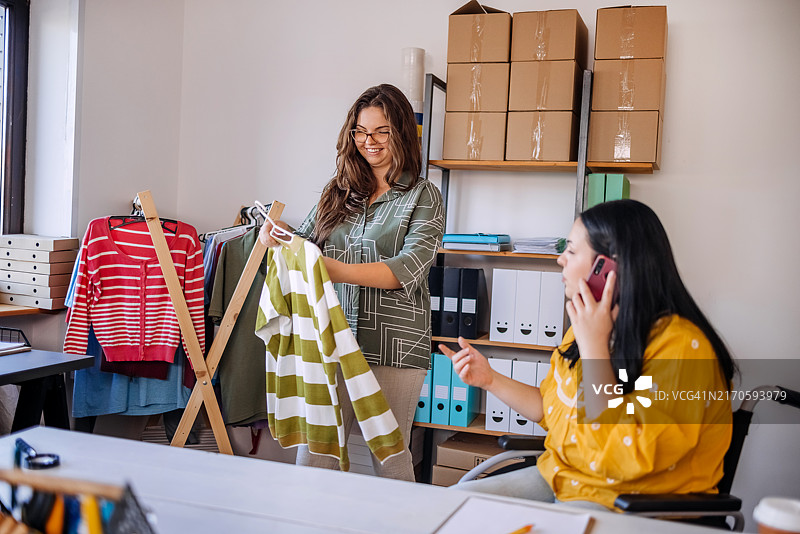 年轻女人与坐轮椅的女性朋友一起工作，并通过手机接收订单图片素材