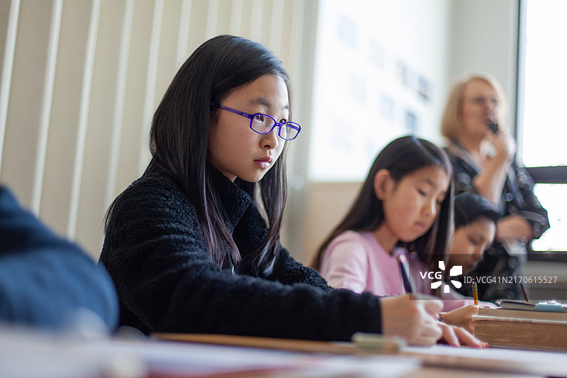 亚洲中国小学初中生女生在课堂上听老师讲课图片素材