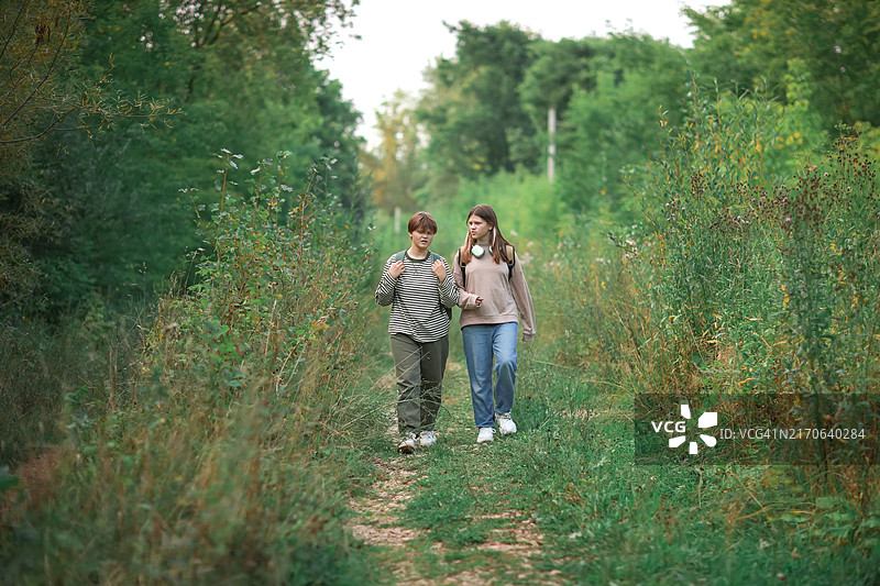 快乐徒步：两个少女在公园小径上愉快交谈图片素材