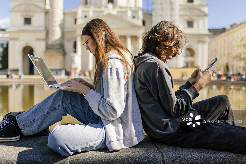 青少年兄妹坐在维也纳卡尔教堂前图片素材