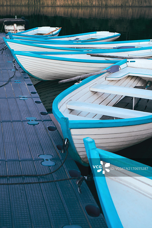 停靠在码头上的彩色木船，在清晨的阳光下反射着宁静的水面图片素材
